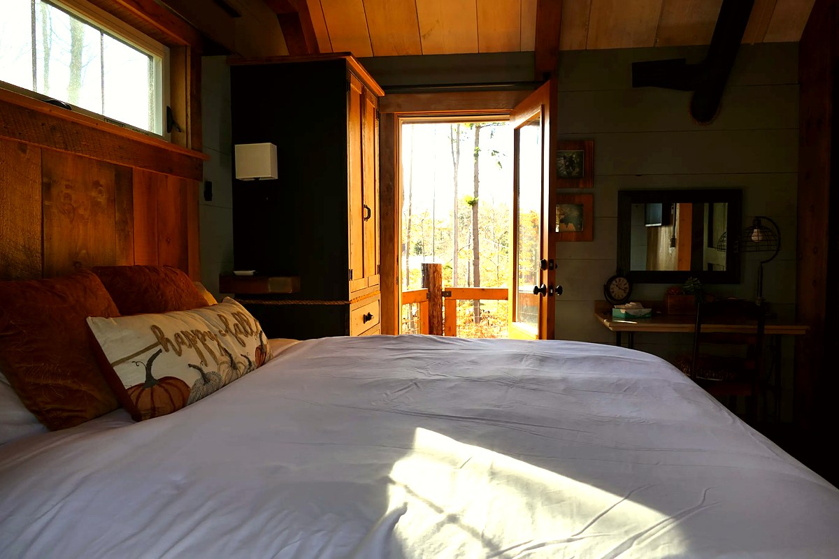 Master suite with king bed and open door to the private balcony with mountain views