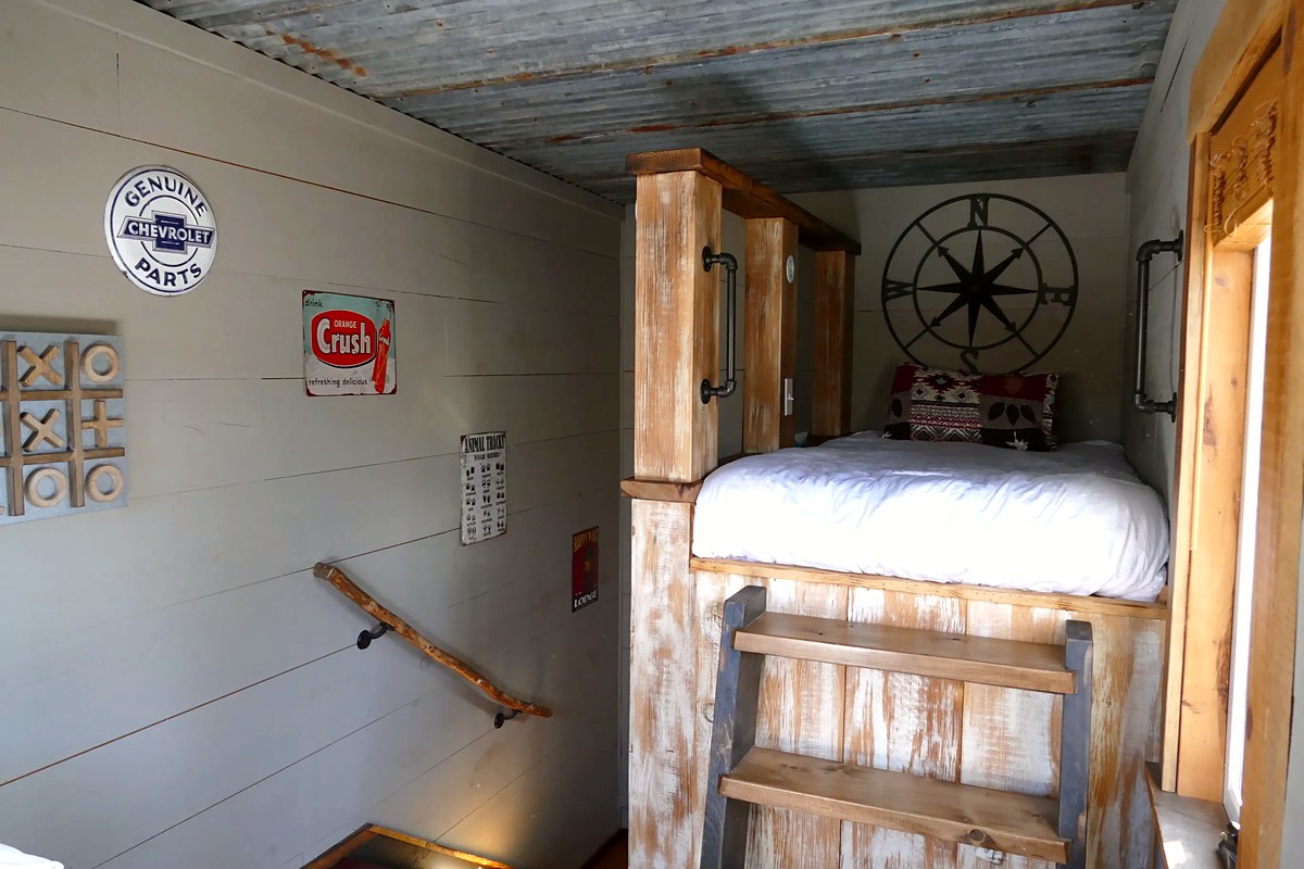The Cub Den — bunk bed with compass rose, vintage signs, and corrugated tin ceiling